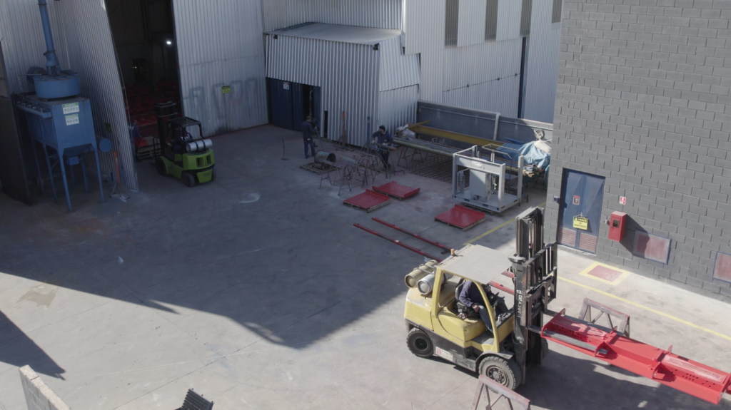 Empilhadeira movimentando estruturas no pátio da fábrica